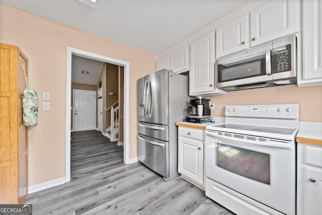 kitchen featuring light hardwood / wood-style flooring, white cabinetry, stainless steel appliances, and a textured ceiling