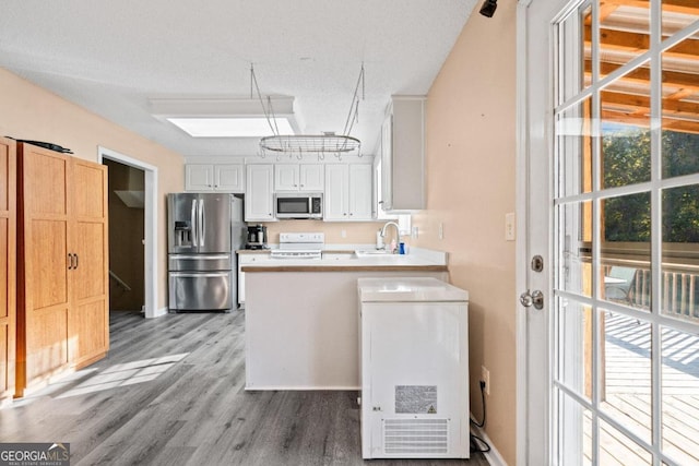 kitchen with light hardwood / wood-style flooring, stainless steel appliances, sink, white cabinets, and a textured ceiling