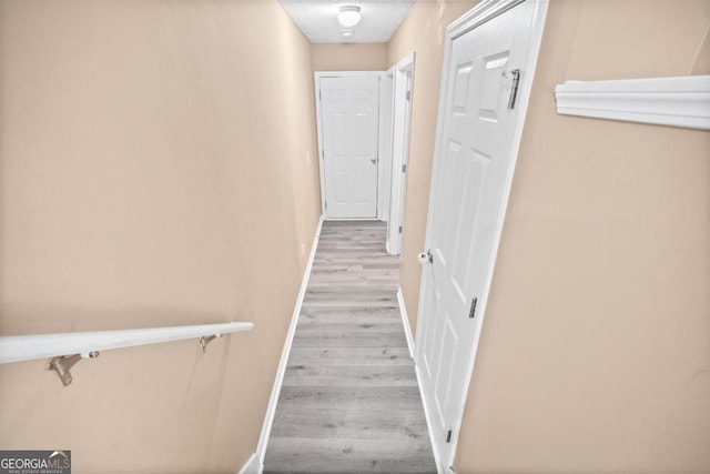 corridor with light hardwood / wood-style flooring and a textured ceiling