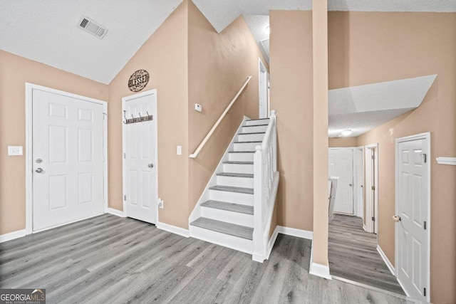 foyer featuring lofted ceiling, a textured ceiling, and light hardwood / wood-style flooring