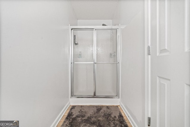 bathroom featuring an enclosed shower and a textured ceiling