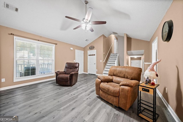 living room featuring a textured ceiling, hardwood / wood-style flooring, ceiling fan, and vaulted ceiling