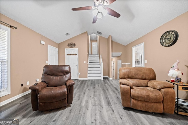 living room featuring ceiling fan, wood-type flooring, and vaulted ceiling