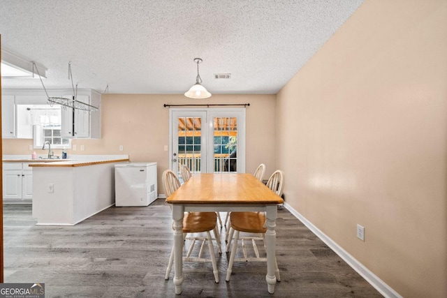 dining area featuring sink, a textured ceiling, and hardwood / wood-style flooring