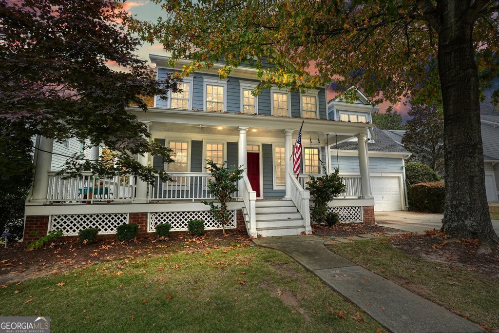 colonial-style house with a lawn, a porch, and a garage