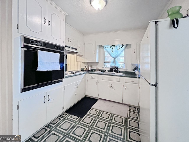 kitchen with white appliances, white cabinetry, sink, and a textured ceiling