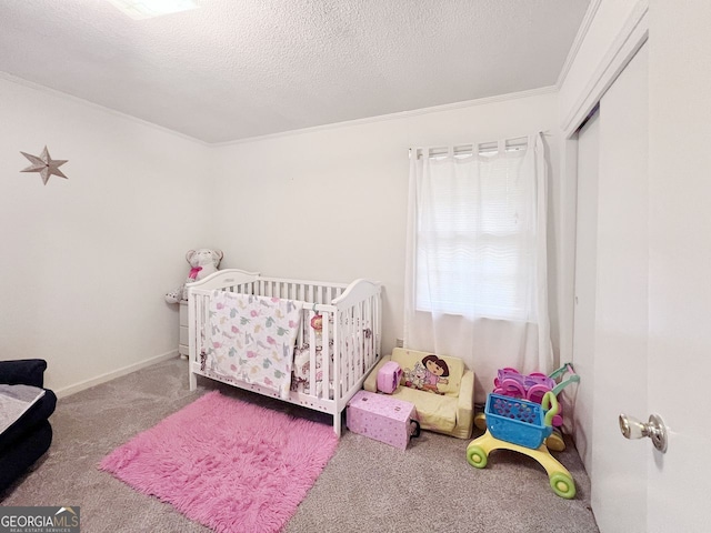 carpeted bedroom with a nursery area, a textured ceiling, and ornamental molding