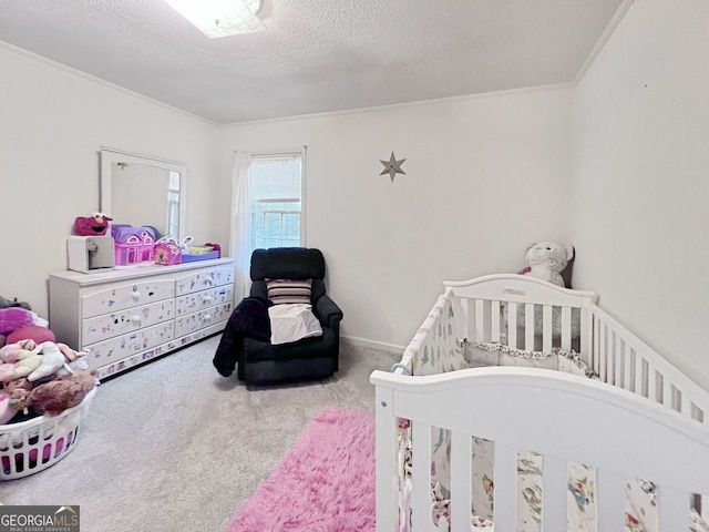 bedroom featuring ornamental molding, a textured ceiling, a nursery area, and carpet floors