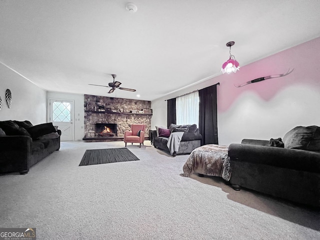 living room with a stone fireplace, light colored carpet, and ceiling fan