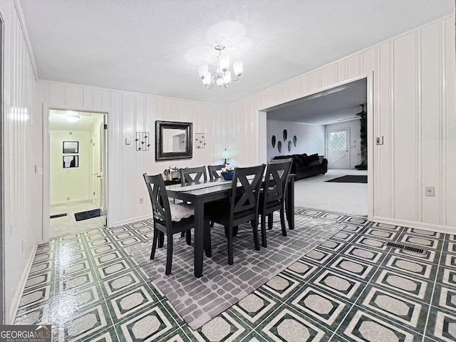 carpeted dining space featuring a textured ceiling and ceiling fan with notable chandelier