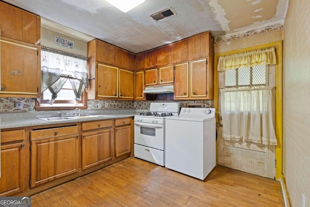 kitchen featuring white gas stove, washer / clothes dryer, sink, tasteful backsplash, and light hardwood / wood-style flooring