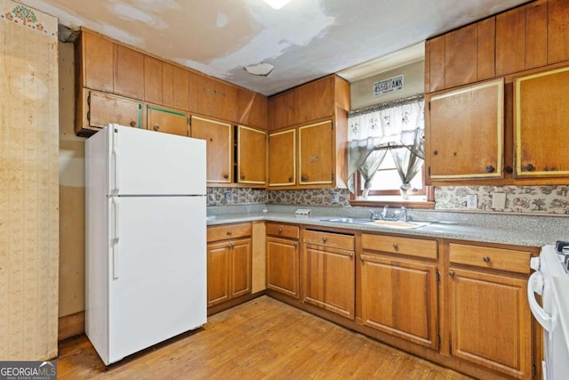 kitchen with sink, light hardwood / wood-style floors, decorative backsplash, and white appliances