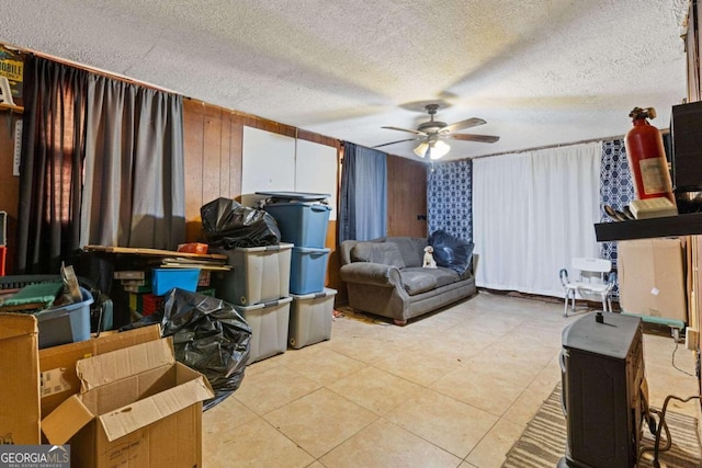 interior space featuring wood walls, a textured ceiling, and ceiling fan