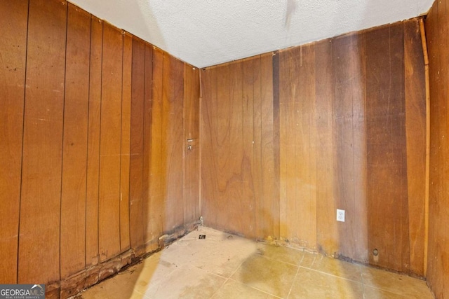 unfurnished room featuring a textured ceiling and wooden walls