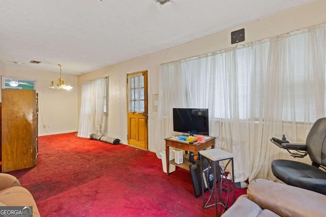 carpeted living room with an inviting chandelier and a healthy amount of sunlight