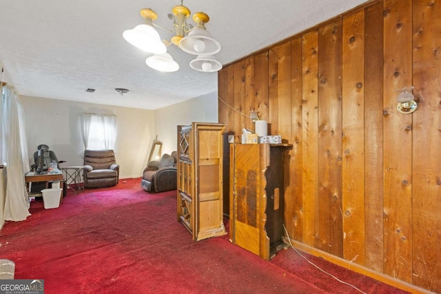 living area with an inviting chandelier, a textured ceiling, and dark carpet