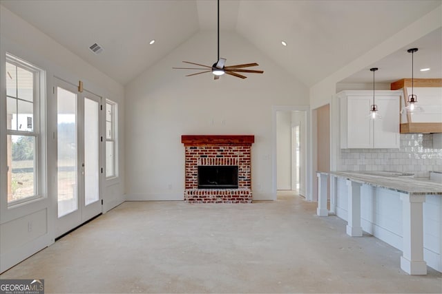 unfurnished living room with ceiling fan, a fireplace, and high vaulted ceiling