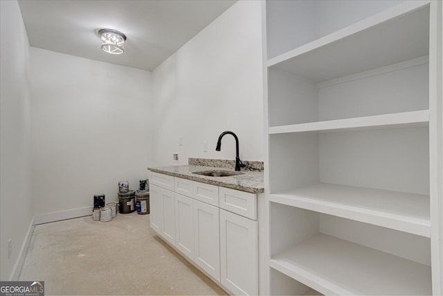 bar featuring white cabinetry, sink, and light stone countertops