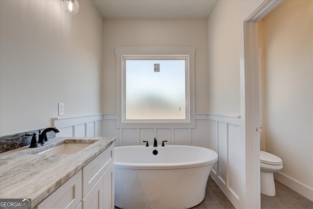 bathroom featuring tile patterned flooring, vanity, toilet, and a bathing tub