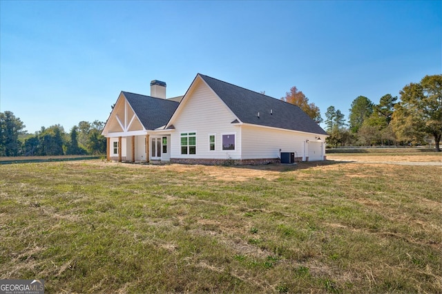 rear view of house with central AC and a lawn