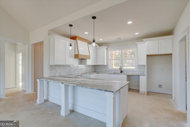 kitchen with pendant lighting, a center island, white cabinets, decorative backsplash, and light stone counters