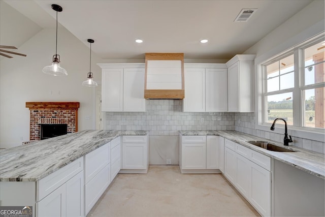 kitchen featuring backsplash, lofted ceiling, white cabinetry, and sink