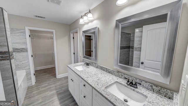 bathroom featuring vanity, hardwood / wood-style floors, and tiled shower