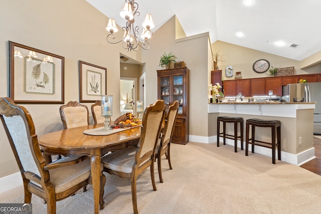 carpeted dining space featuring a chandelier and high vaulted ceiling