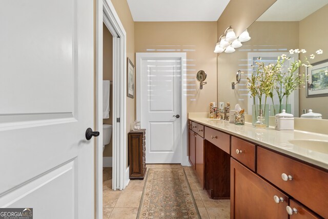 bathroom with toilet, vanity, and tile patterned floors