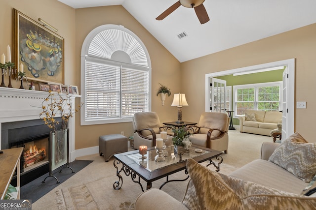 carpeted living room with ceiling fan and vaulted ceiling