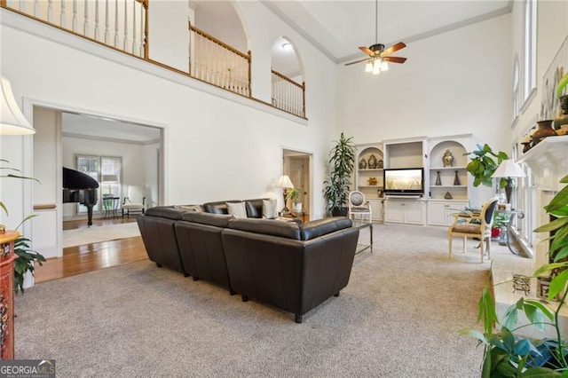 living room with carpet, high vaulted ceiling, ceiling fan, and built in features