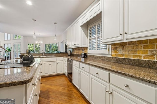 kitchen featuring white cabinets, dishwasher, light wood-type flooring, and black cooktop