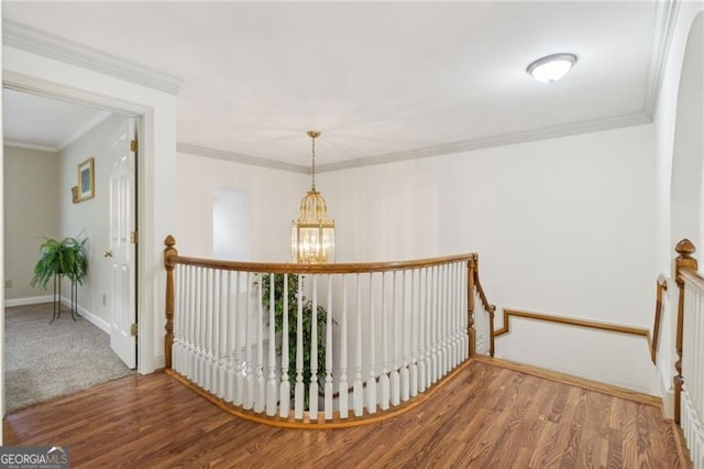 hallway with hardwood / wood-style flooring, crown molding, and an inviting chandelier