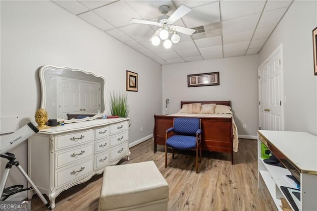 bedroom with a paneled ceiling, light hardwood / wood-style flooring, and ceiling fan