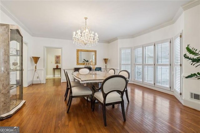 dining space featuring hardwood / wood-style flooring, an inviting chandelier, and crown molding