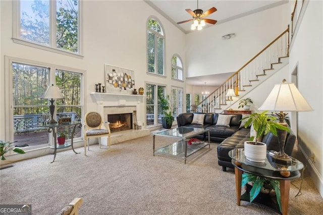 living room featuring plenty of natural light, a towering ceiling, a fireplace, and carpet floors