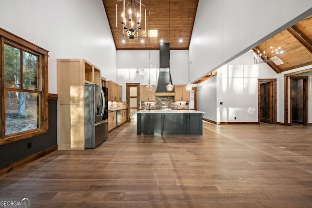 kitchen with a center island with sink, pendant lighting, an inviting chandelier, and stainless steel fridge