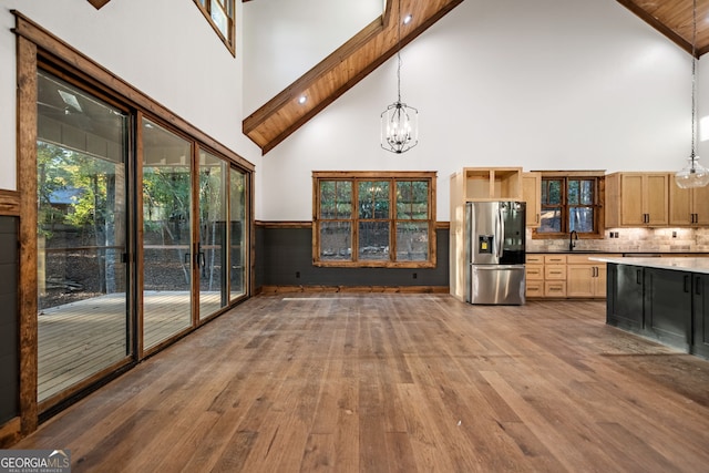 kitchen with hardwood / wood-style flooring, stainless steel refrigerator with ice dispenser, high vaulted ceiling, a chandelier, and pendant lighting