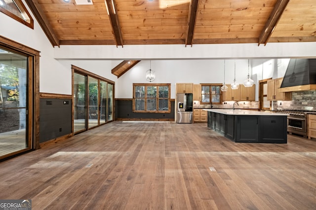 kitchen with stainless steel appliances, decorative light fixtures, wooden ceiling, custom exhaust hood, and a kitchen island with sink