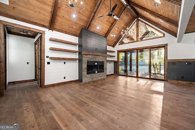 unfurnished living room with beam ceiling, hardwood / wood-style flooring, a stone fireplace, high vaulted ceiling, and wood ceiling