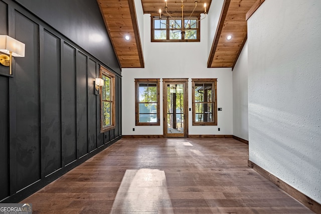 foyer entrance with a notable chandelier, a high ceiling, wooden ceiling, and dark hardwood / wood-style floors