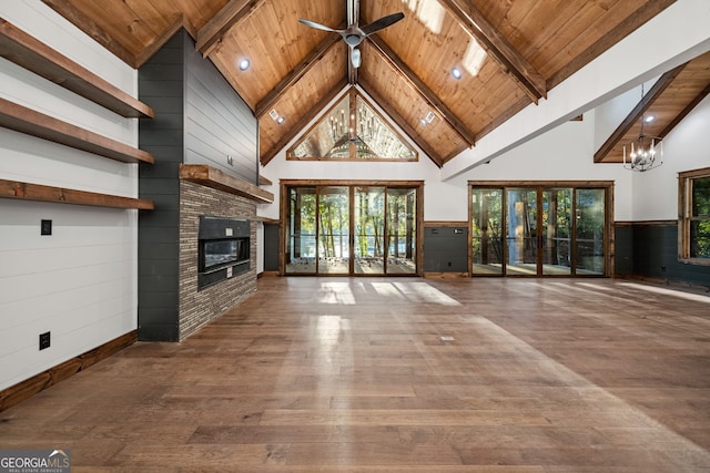 unfurnished living room featuring hardwood / wood-style flooring, beam ceiling, wood ceiling, high vaulted ceiling, and ceiling fan with notable chandelier