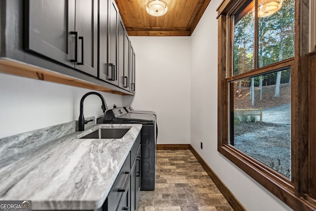 clothes washing area featuring sink, washer and clothes dryer, cabinets, and wooden ceiling