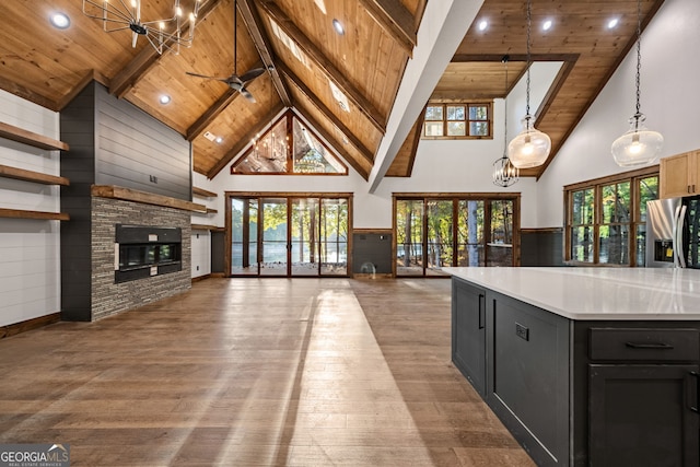 kitchen with pendant lighting, a stone fireplace, stainless steel fridge with ice dispenser, light hardwood / wood-style floors, and wooden ceiling