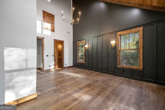 empty room featuring hardwood / wood-style floors, an inviting chandelier, and a high ceiling