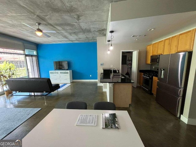 kitchen featuring a kitchen island with sink, stainless steel appliances, sink, pendant lighting, and ceiling fan