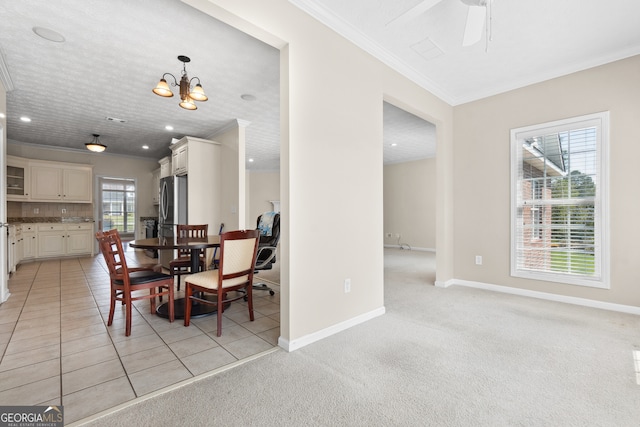 dining area with light carpet, ornamental molding, and ceiling fan with notable chandelier