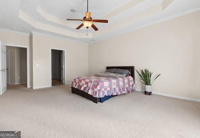 carpeted bedroom with ornamental molding, a tray ceiling, and ceiling fan