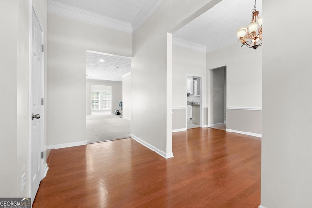 unfurnished room featuring hardwood / wood-style floors, crown molding, and an inviting chandelier