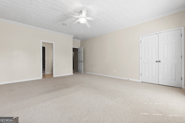 unfurnished bedroom featuring a textured ceiling, a closet, ceiling fan, light carpet, and ornamental molding